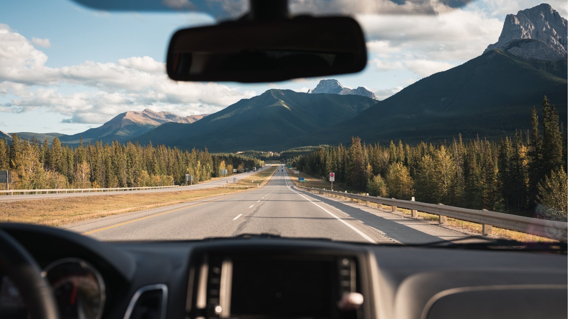 A vehicle driving along a paved road toward snow-capped mountains, representing Integrity’s focus on safe driving across Western Canada.